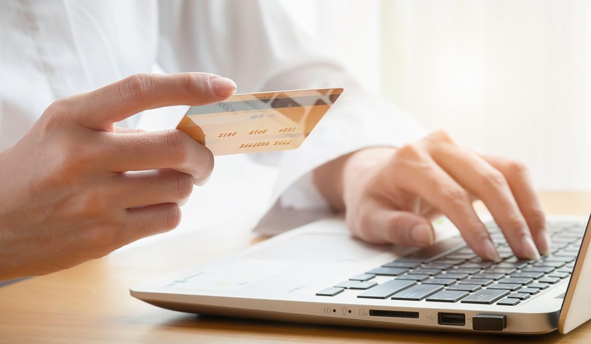 hand-of-woman-holding-credit-card-to-shopping-onli-2024-11-29-22-37-28-utc Hands of woman buys online holding a credit card with a laptop on the table . Shopping online concept.