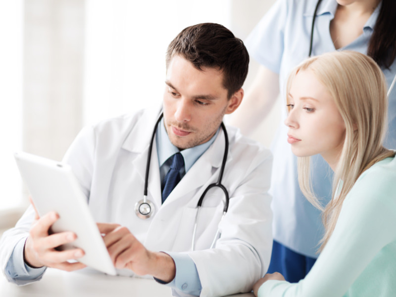 Young male doctor reviews TOS test results with young blonde woman patient