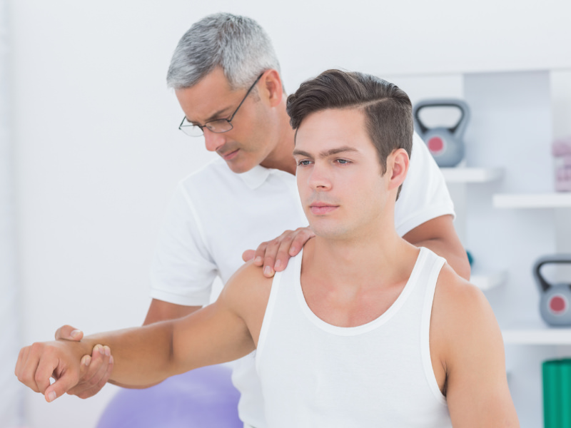 Silver-haired TOS therapist examines patient’s painful arm