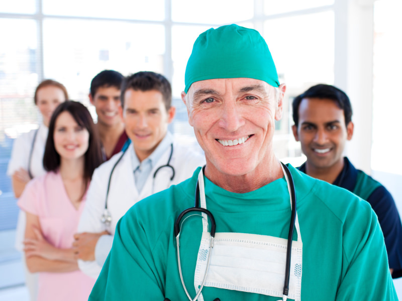 TOS specialists in hospital hallway led by surgeon in green scrubs
