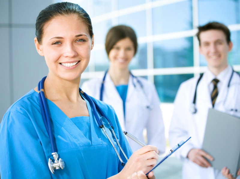 Smiling female TOS specialist in blue scrubs with TOS team